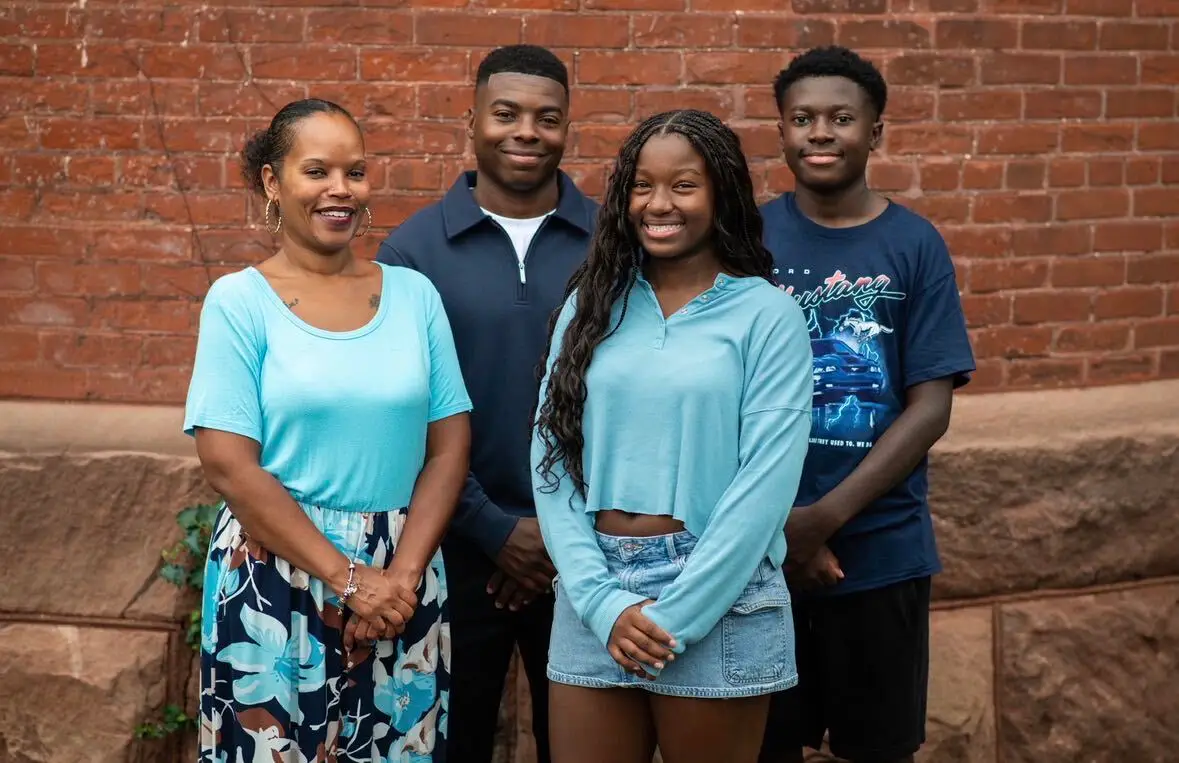 April with her family, standing together in front of a brick wall